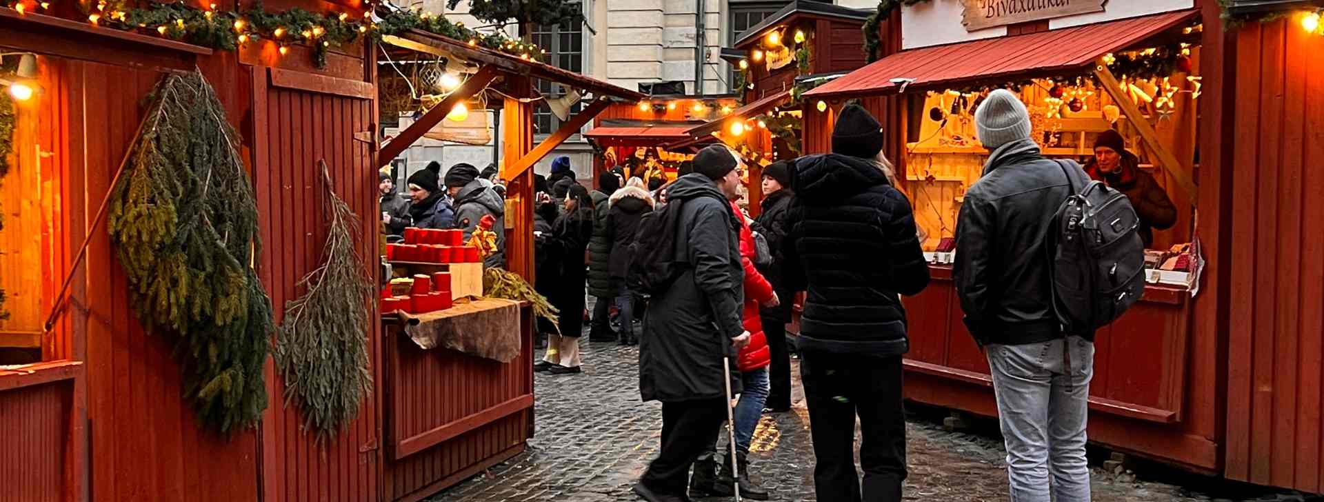 Menschen auf dem Weihnachtsmarkt Stortorgets Julmarknad - die Hütten sind rot gestrichen