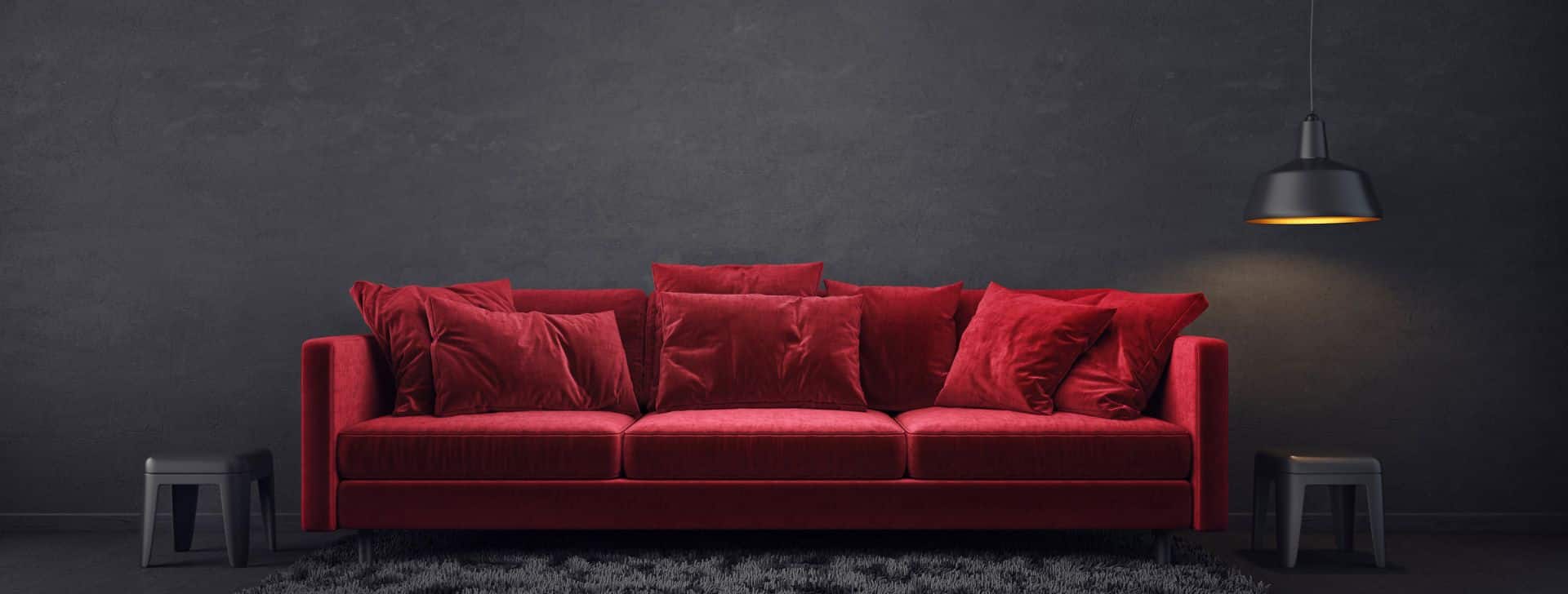 eine dunkelrote Couch von grauer Wand