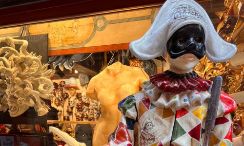Ein Karnevalskostüm vor einer Auslage mit Masken